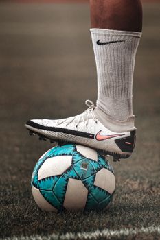 A person in sportswear balancing a blue soccer ball on grassy field.