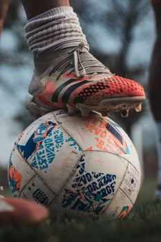 Dynamic close-up of a foot in sports shoe touching a soccer ball on a field.