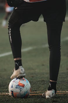 Close-up of a soccer player controlling the ball on a field, wearing branded footwear.