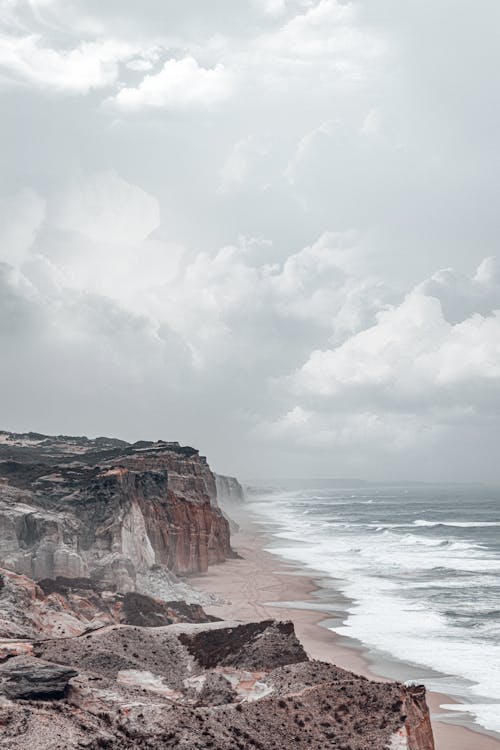 Aerial Photography of Mountains and Sea Shore under the Cloudy Sky