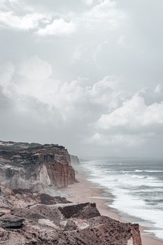 A captivating view of rocky cliffs and waves under a cloudy sky, showcasing nature's raw beauty.