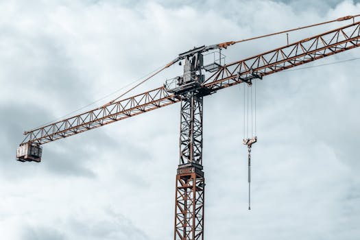 A tall construction crane under cloudy skies, perfect for industry-themed projects.