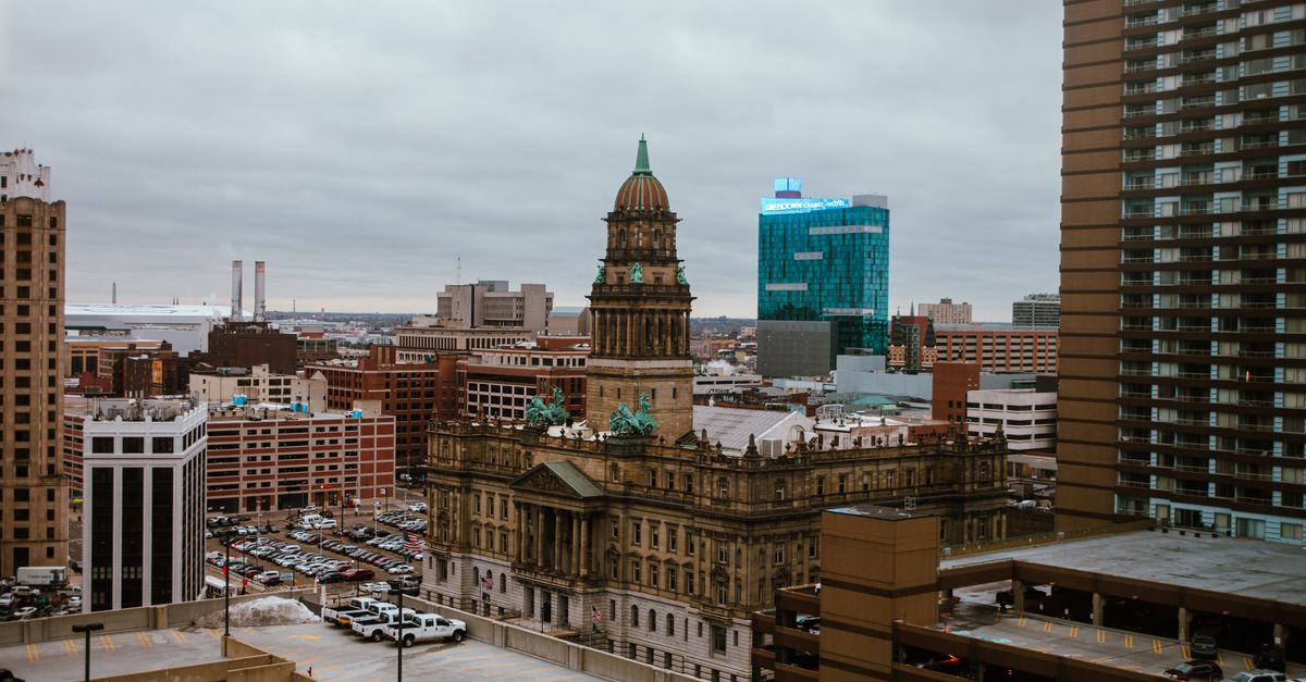 Aerial view of Detroit city showcasing historic and modern buildings under a cloudy sky.