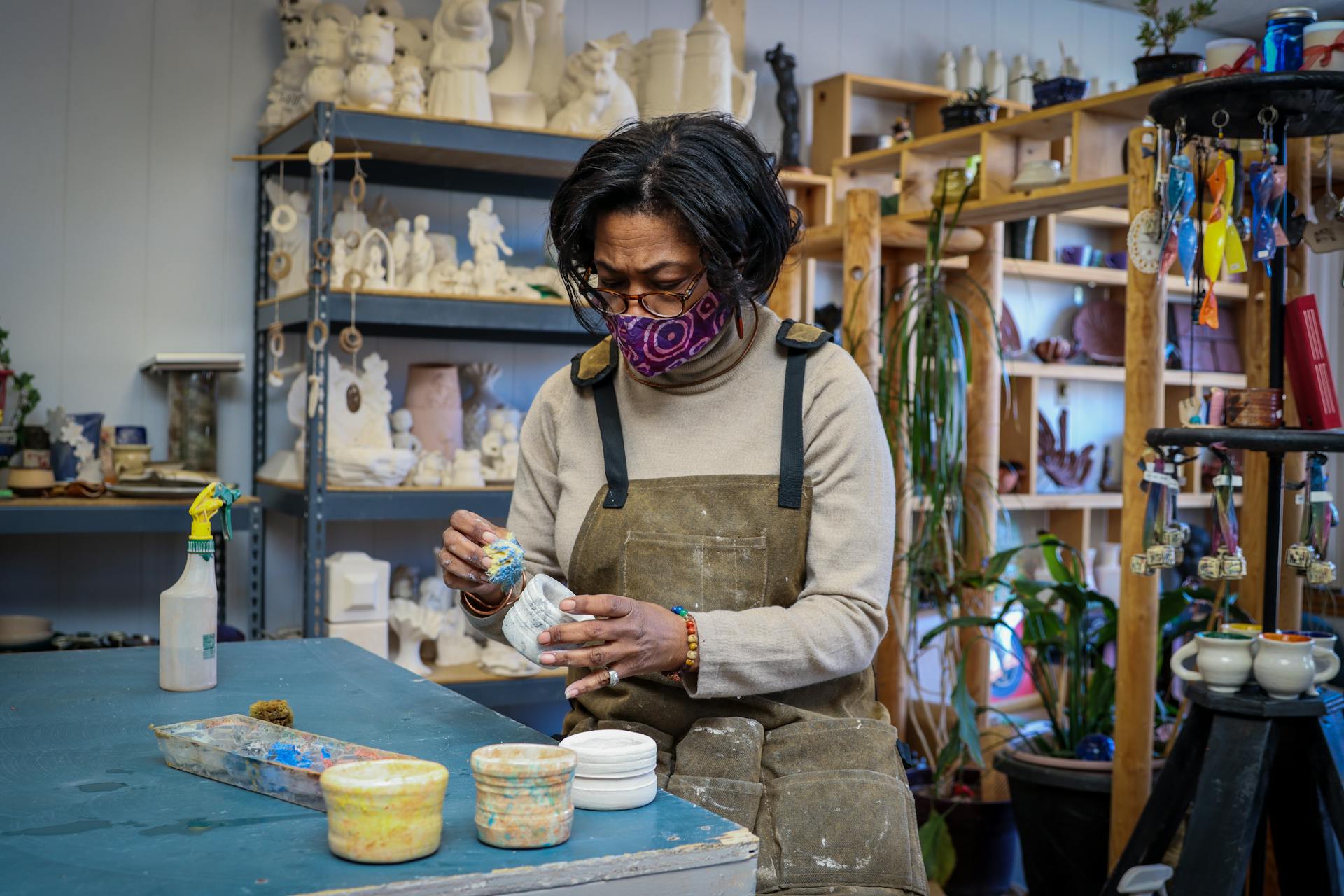 African American woman crafting pottery in a vibrant Detroit workshop.