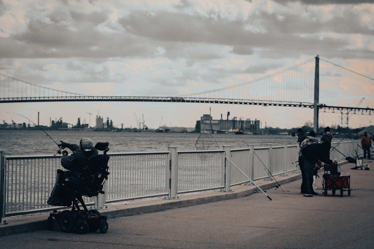 People Fishing On Detroit River Near A Bridge