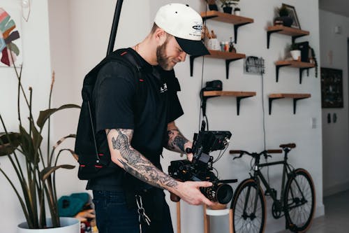 Man in Black T-shirt and White Cap Holding Black Video Camera