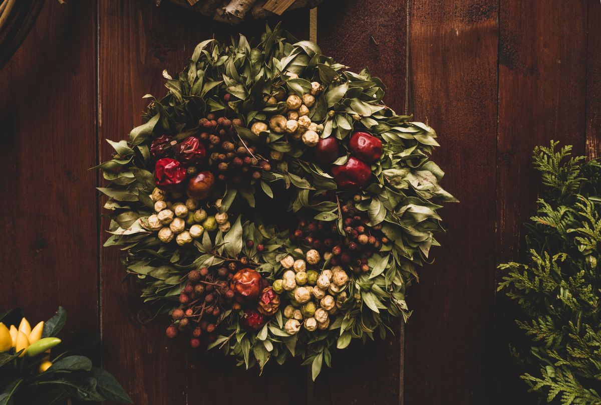 Green and red berry wreath hanging on a rustic wooden door