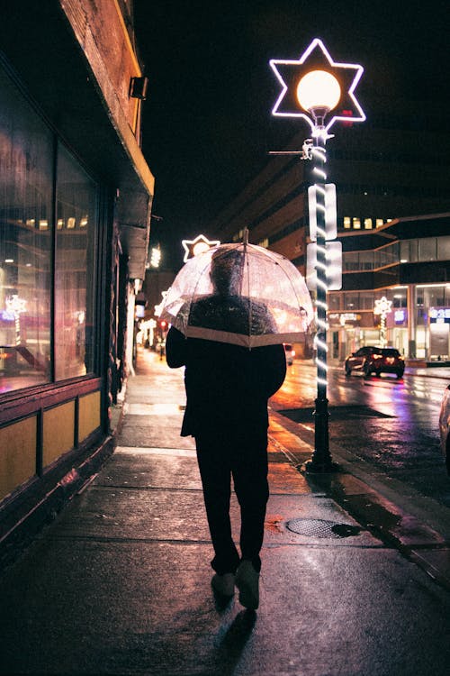 Man Walking in City under Umbrella