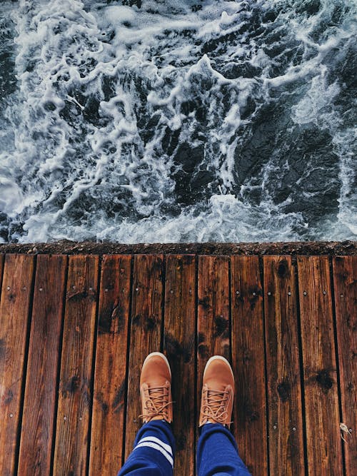 Person Wearing Brown Shoes Standing on Wooden Dock