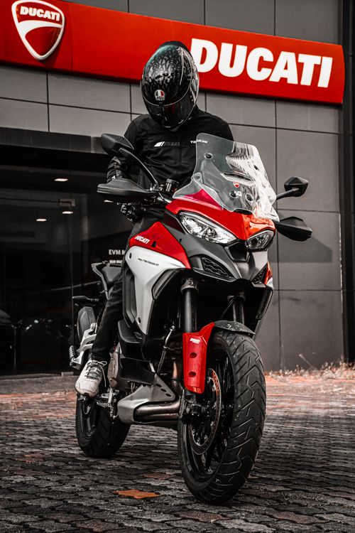 Free A motorcyclist in full gear poses on a Ducati motorcycle outside a showroom. Stock Photo