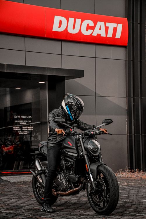Free Motorcycle enthusiast riding a Ducati sports bike in front of a dealership. Stock Photo