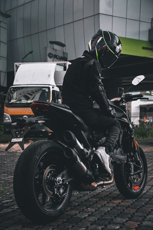 A Man in Black Clothing Riding a Black Motorcycle