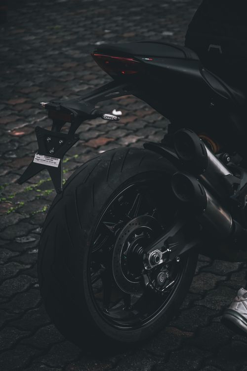 Free Close-up shot of a stylish black motorcycle rear wheel on cobblestone pavement. Stock Photo