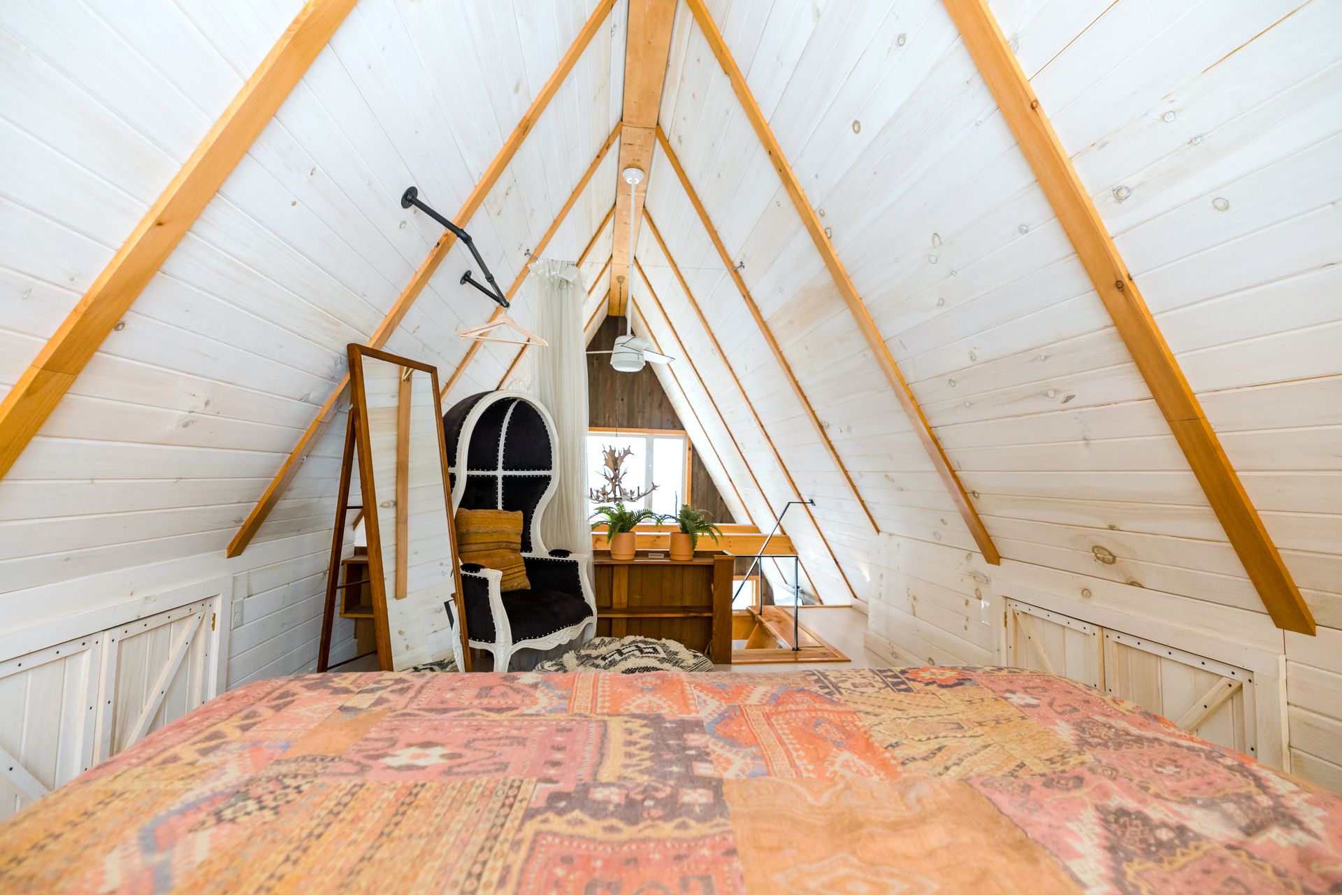 Warm attic bedroom in Stowe, Vermont with wooden beams and rustic decor.