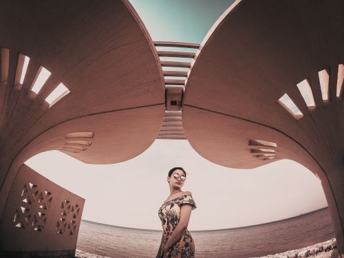 Free Fashion model posing under futuristic architecture by the sea in Saudi Arabia. Stock Photo