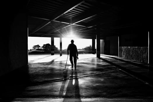 Black and white silhouette of a person walking in a sunlit parking structure in Santiago de Querétaro.