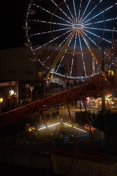 Captivating evening shot of a Ferris wheel and attractions at a vibrant fairground.