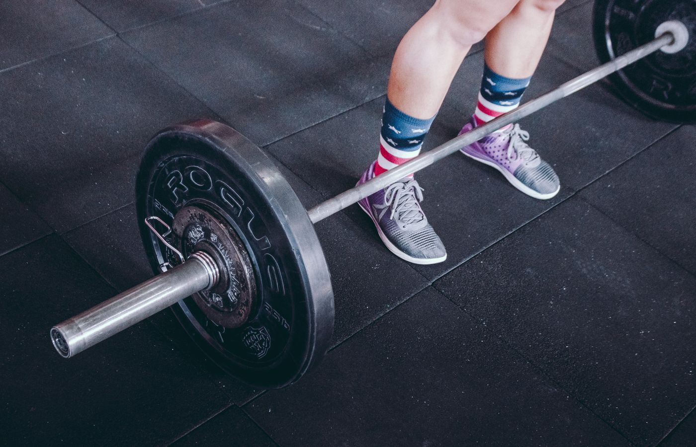 Person preparing to lift a barbell with patriotic socks in a gym.