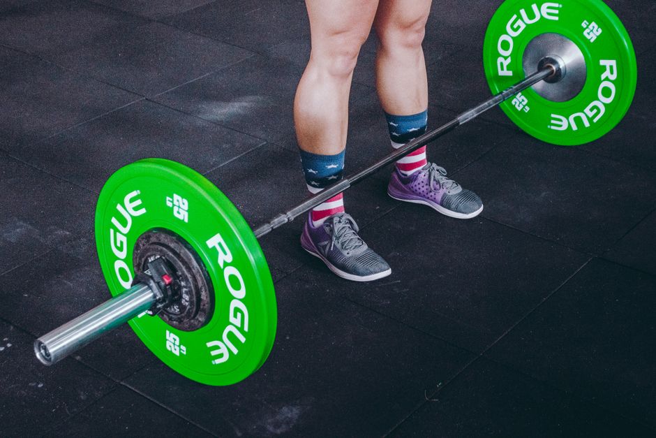 Focused view of legs and barbell at the gym, emphasizing strength and fitness.