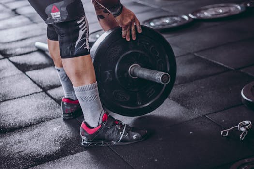 A focused man lifting a heavy barbell during weightlifting exercise in a gym.
