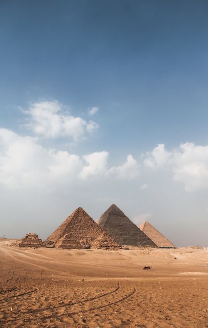 Explore the stunning Giza Pyramids under a vibrant blue sky, showcasing ancient architecture and desert scenery.