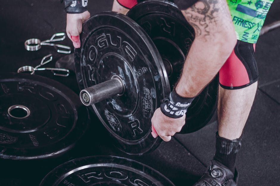 Close-up of a weightlifter lifting barbells in a gym setting, focusing on strength and fitness.