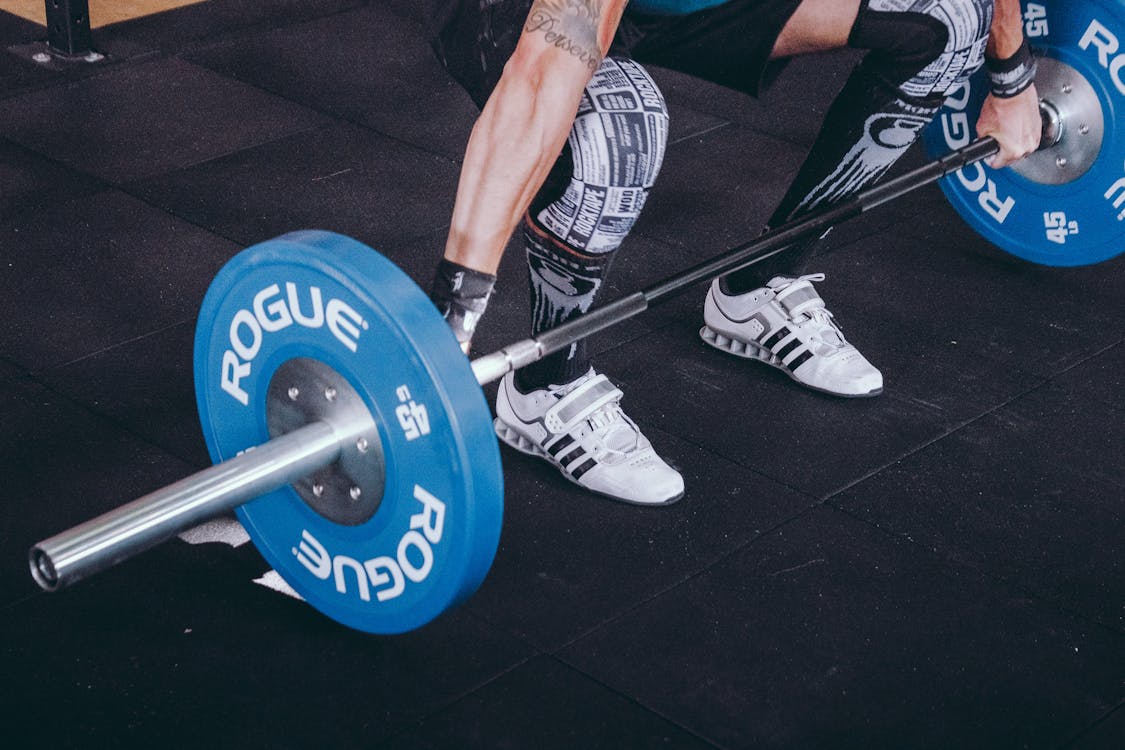 Free Man With Lift Stance Holds Blue Rogue Adjustable Barbell Stock Photo