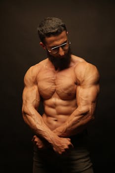 Studio shot of a shirtless muscular man flexing his muscles showing strength and fitness.