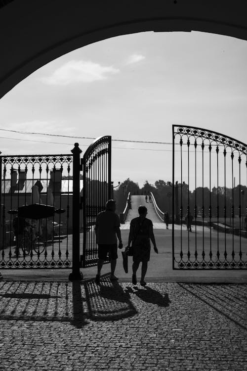 Silhouette of People Near a Metal Gate