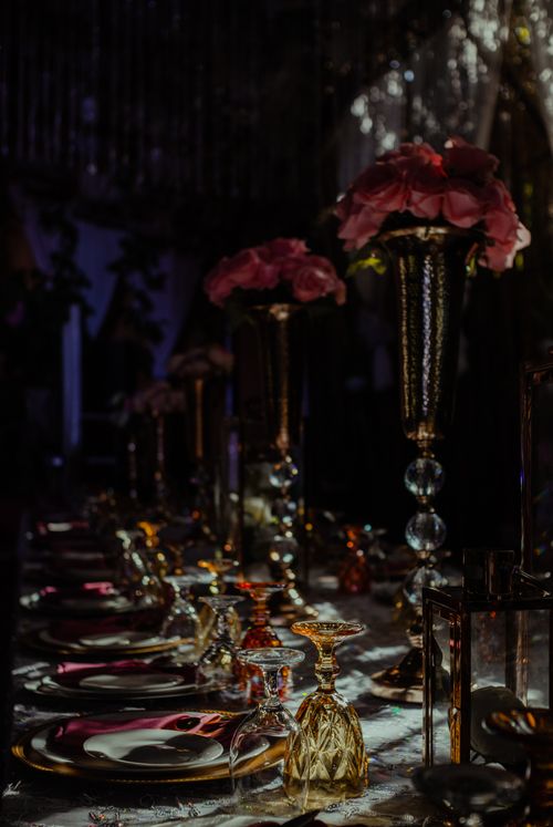 Free Luxurious table setting with pink roses and crystal glassware, creating a moody, formal ambiance. Stock Photo