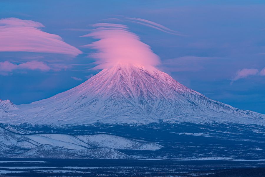 Volcán nevado al amanecer con nubes lenticulares