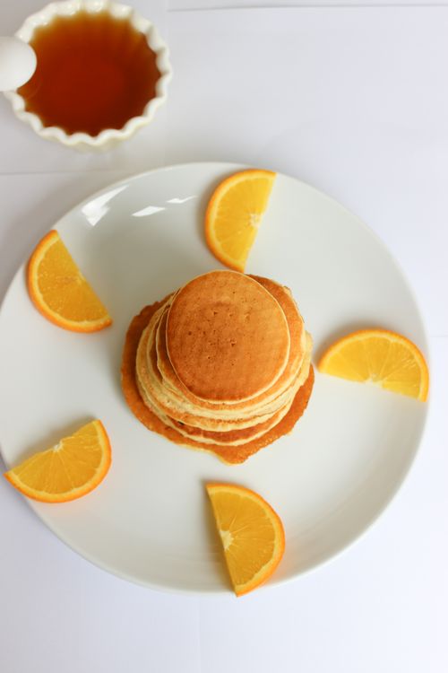 Free Top view of mini pancakes stacked with orange slices and syrup, perfect for a bright breakfast. Stock Photo