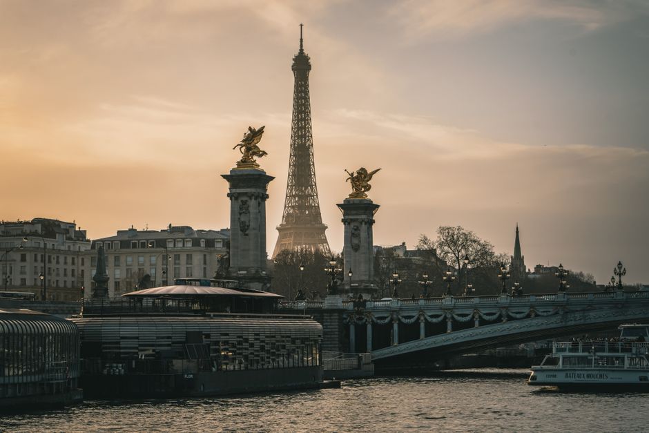 A stunning sunset view of the Eiffel Tower and Pont Alexandre III over the river in Paris.
