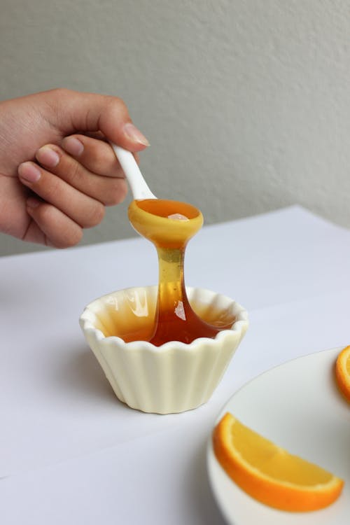 Person Holding a Spoon with Honey 