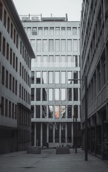 Symmetrical view of modern glass buildings in an urban alley during a gloomy day.