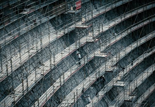 Detailed view of scaffolding on a massive construction site with workers.