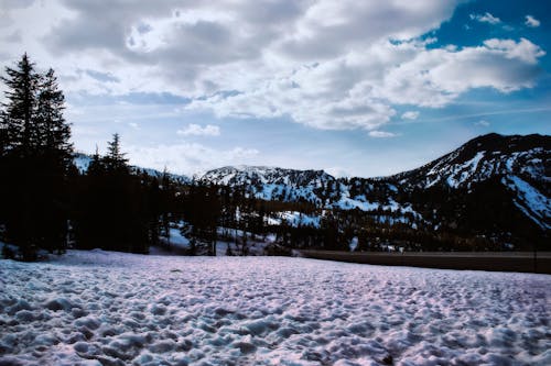 Montaña Cubierta De Nieve Bajo Nubes Blancas Y Cielo Azul