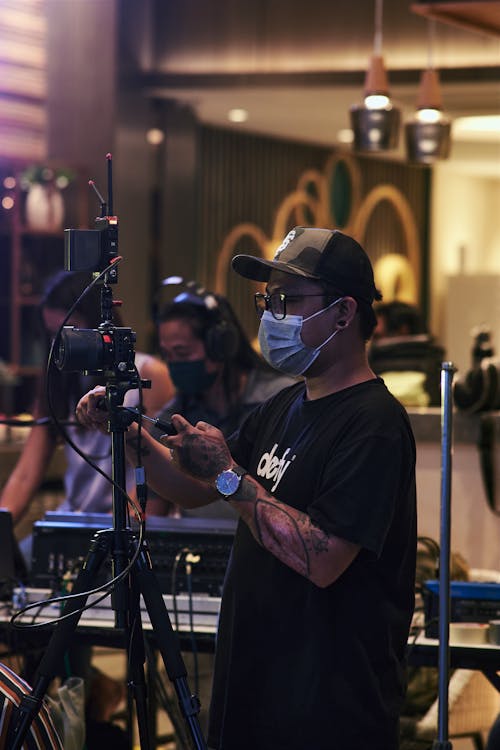 Man in Black Shirt and Cap Filming 