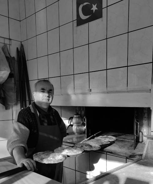 Man Baking Flat Breads in a Kitchen with Turkish Flag