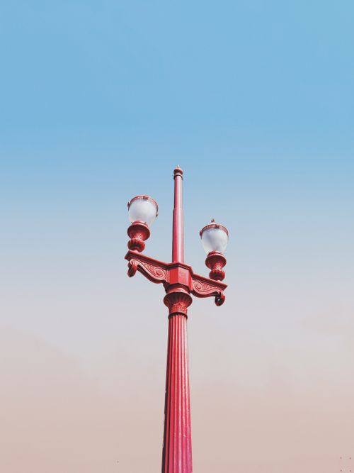 Free Vertical shot of a classic red lamp post against a serene blue sky in Centro, Brazil. Stock Photo
