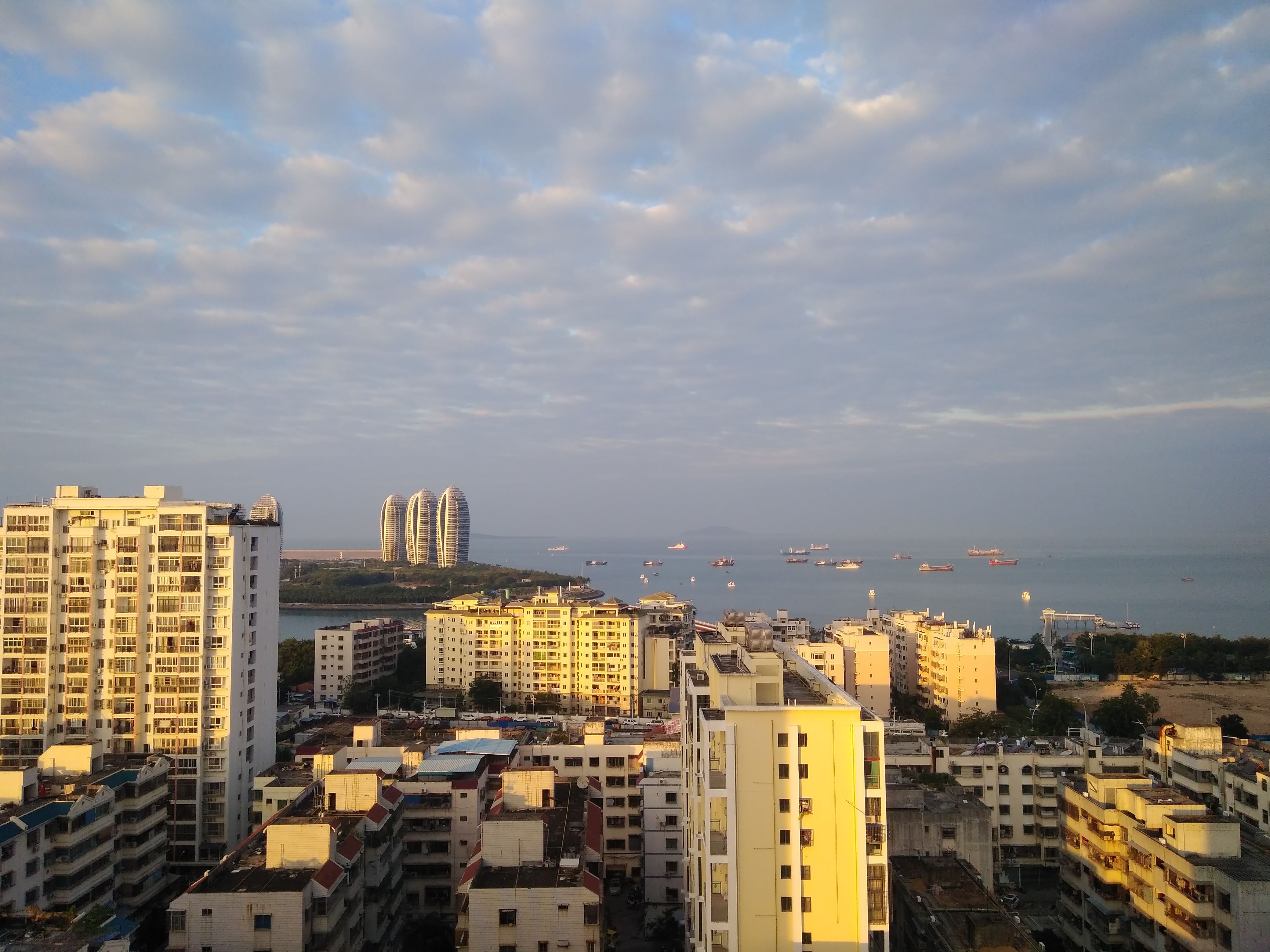 Stunning aerial view of Sanya Bay with the iconic Phoenix Island buildings on a sunny day.