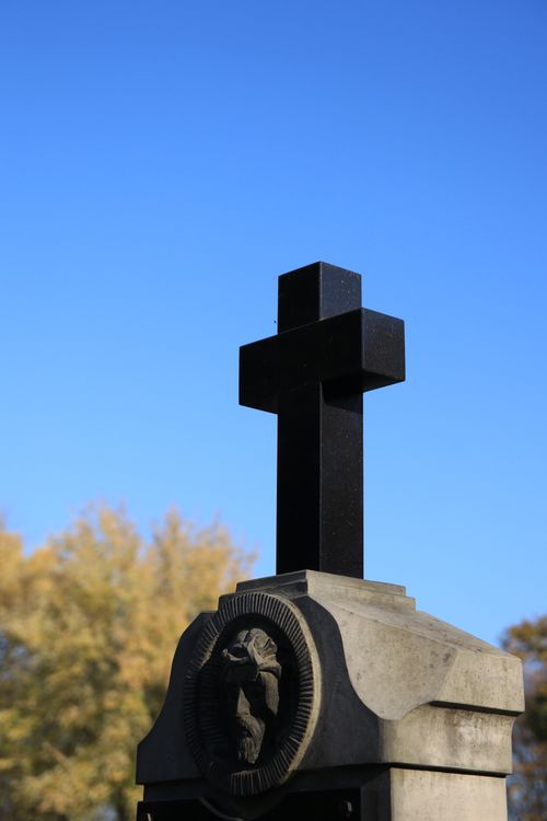 Free A stone cross memorial with decorative engraving under a vibrant clear blue sky, symbolizing peace. Stock Photo