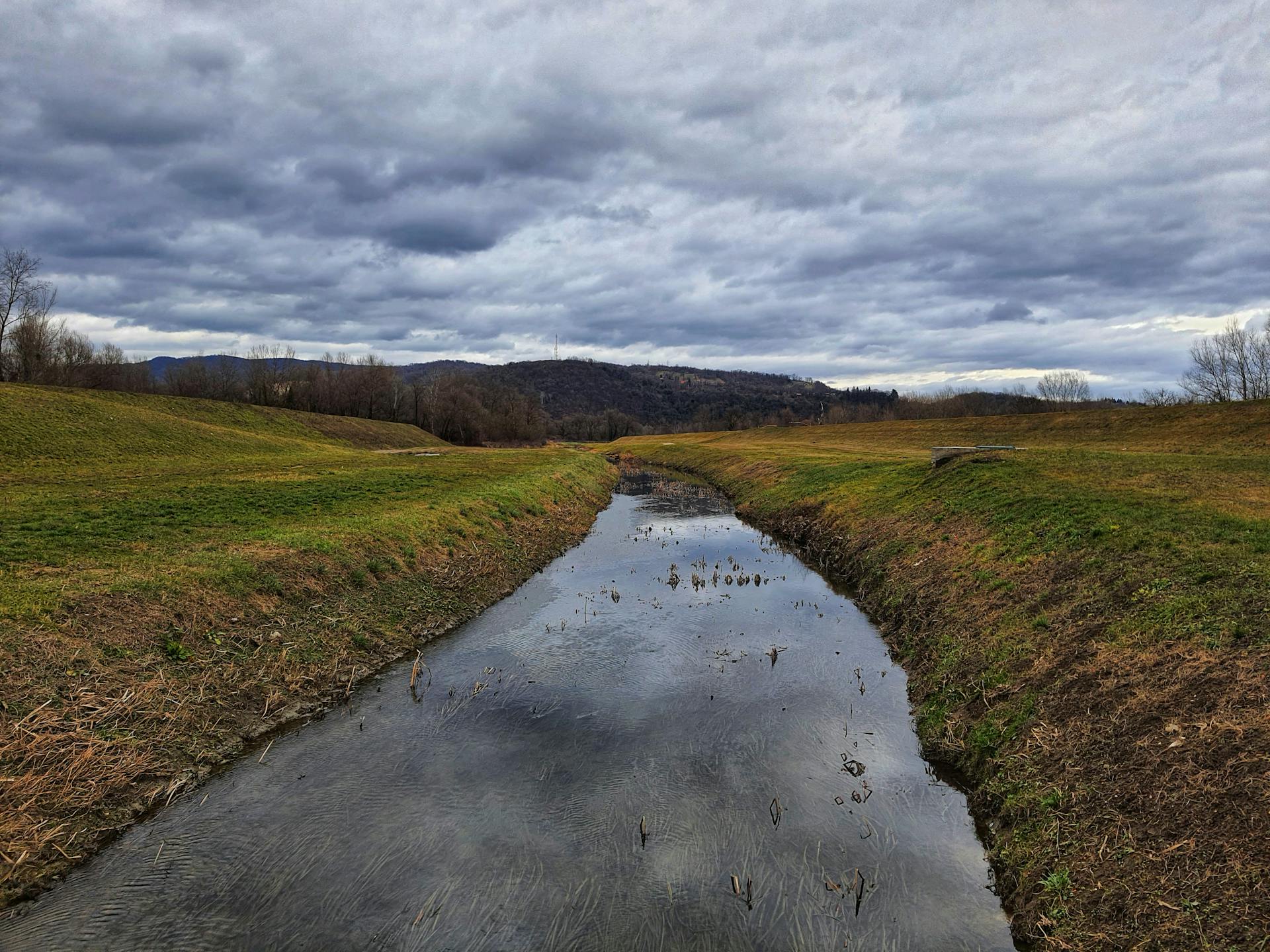 A peaceful river scene with cloudy skies and grassy banks near Zagreb, Croatia.