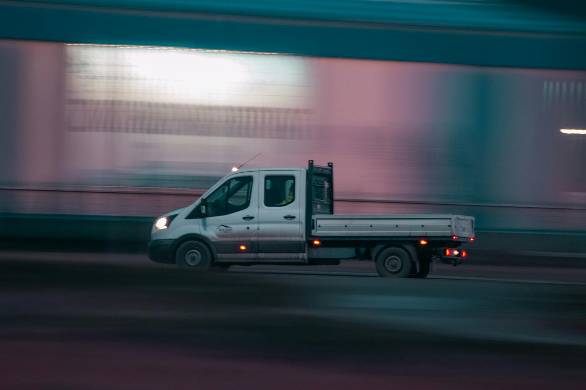 Long exposure shot of a pickup truck moving swiftly at night, capturing motion and urban energy.
