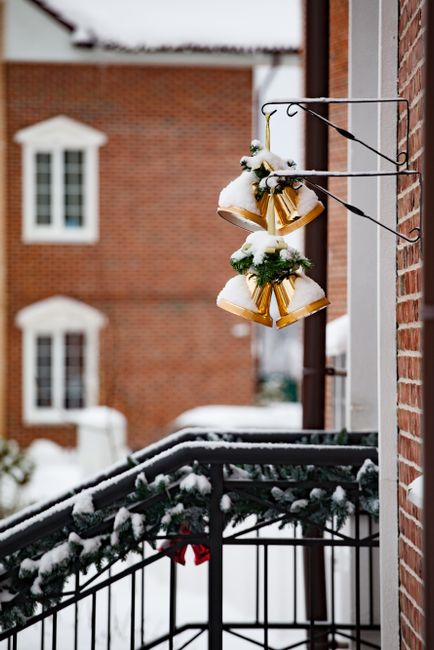 Golden bells with snow on a house entrance railing, capturing a winter season vibe.