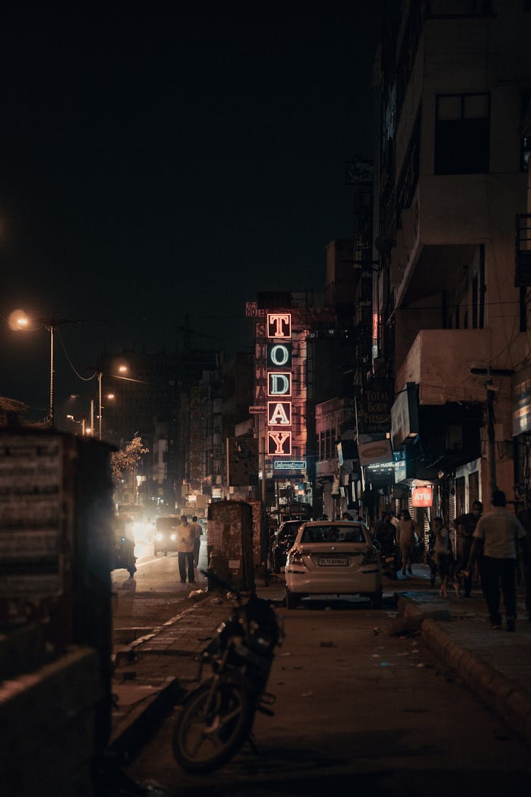 A White Car Parked Near A Today Neon Sign