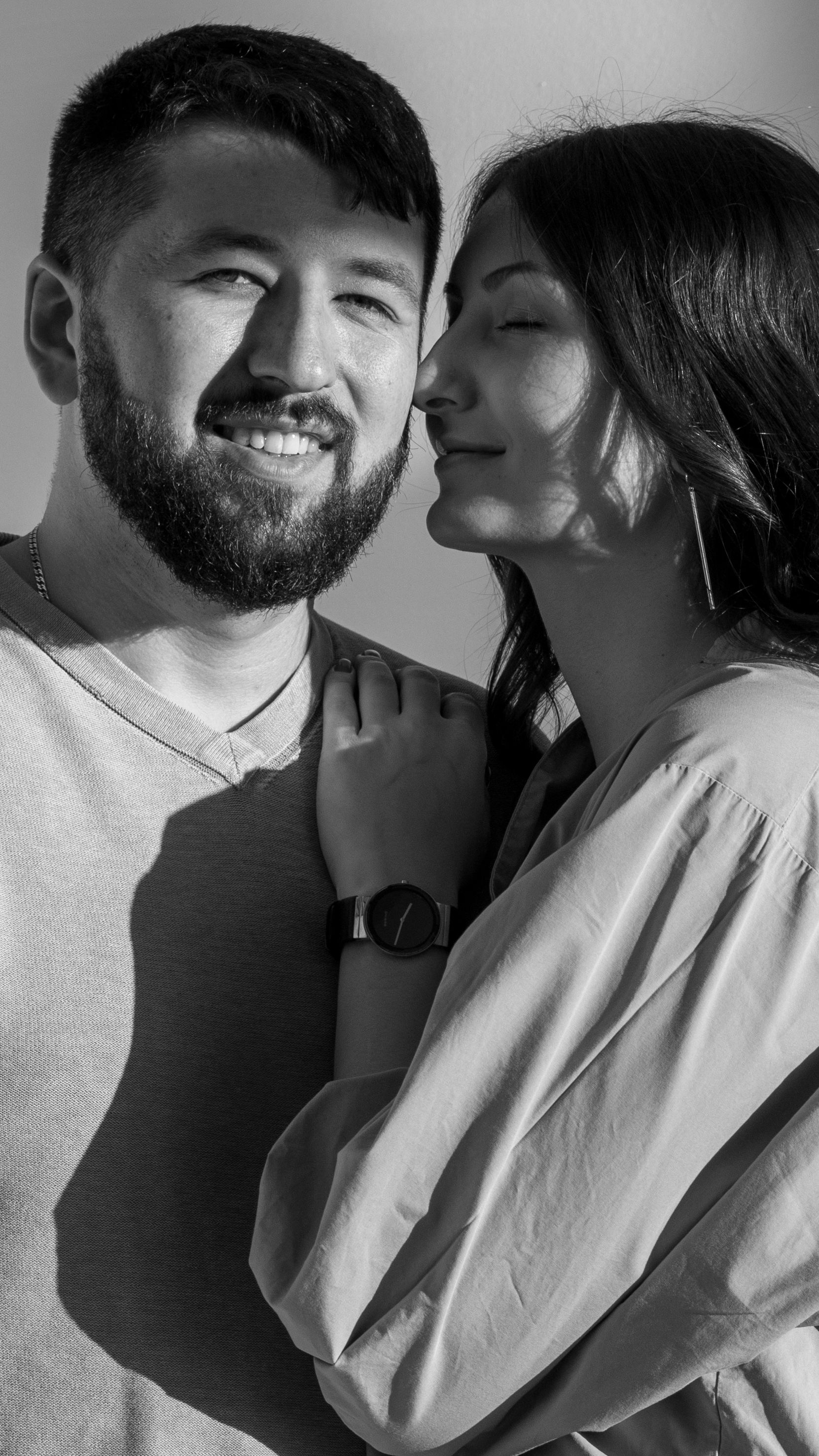 A grayscale image capturing the affectionate and warm connection between a bearded man and a woman.