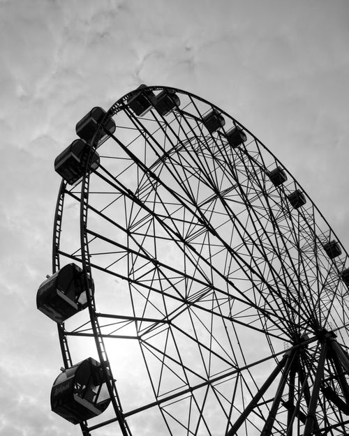 Free A striking monochrome ferris wheel against a cloudy sky, capturing a classic amusement park ride. Stock Photo