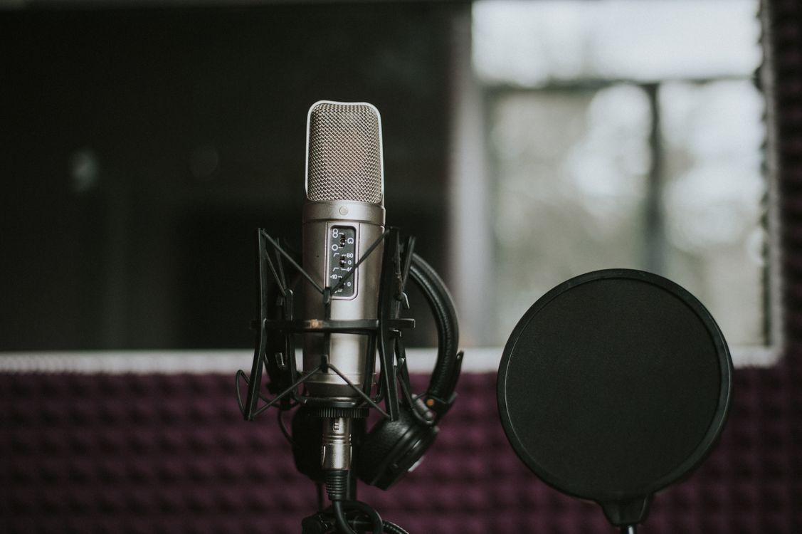 Studijski mikrofon s pop filtrom u prigušeno osvijetljenom studiju