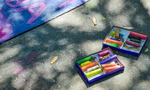 Free Boxes of vibrant chalk on pavement, perfect for street art. Stock Photo